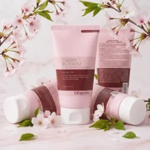 Neljä DERMAL Cherry Blossom Soft White Cleanser 150 g -puhdistusvaahtotuubia aseteltuna vaalealle marmoripinnalle. Yksi tuubi seisoo pystyssä etualalla, yksi takana pystyssä ja kaksi makaa kyljellään sivuilla. Taustalla ja tuotteiden ympärillä on kukkivia kirsikkapuun oksia vaaleanpunaisine kukkineen ja vihreine lehtineen.