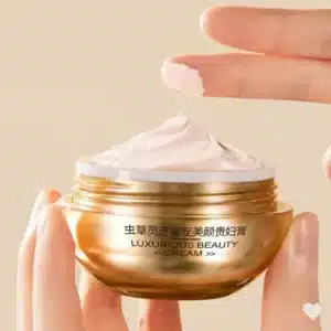 Pyöreä kultainen Mercilen Ganoderma -kasvovoidetölkki ja sen kultainen pakkauslaatikko, jossa on punainen kukkakuvio.