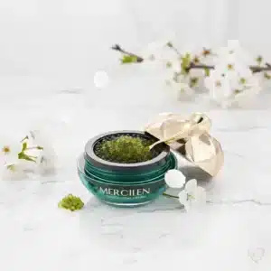 Vihreä Mercilen Merirypäle & Kollageeni -kasvovoidepurkki täynnä vihreitä helmiä, kultainen kansi, lusikka ja pakkaus.