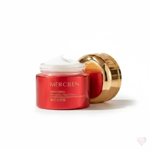 Punainen kultakantinen Mercilen Whitening Cream -kasvovoidepurkki ja pakkaus kirsikankukkien keskellä marmorialustalla.