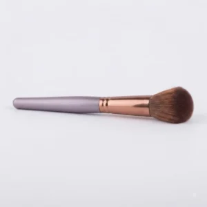 Vaakatasossa aseteltu Paston Makeup Professional -poskipuna- ja varjostussivellin, jossa on hohtava pronssinen metalliholkki, tummanharmaa muotoiltu varsi ja tiheä ruskea harjasosa valkoisella taustalla.