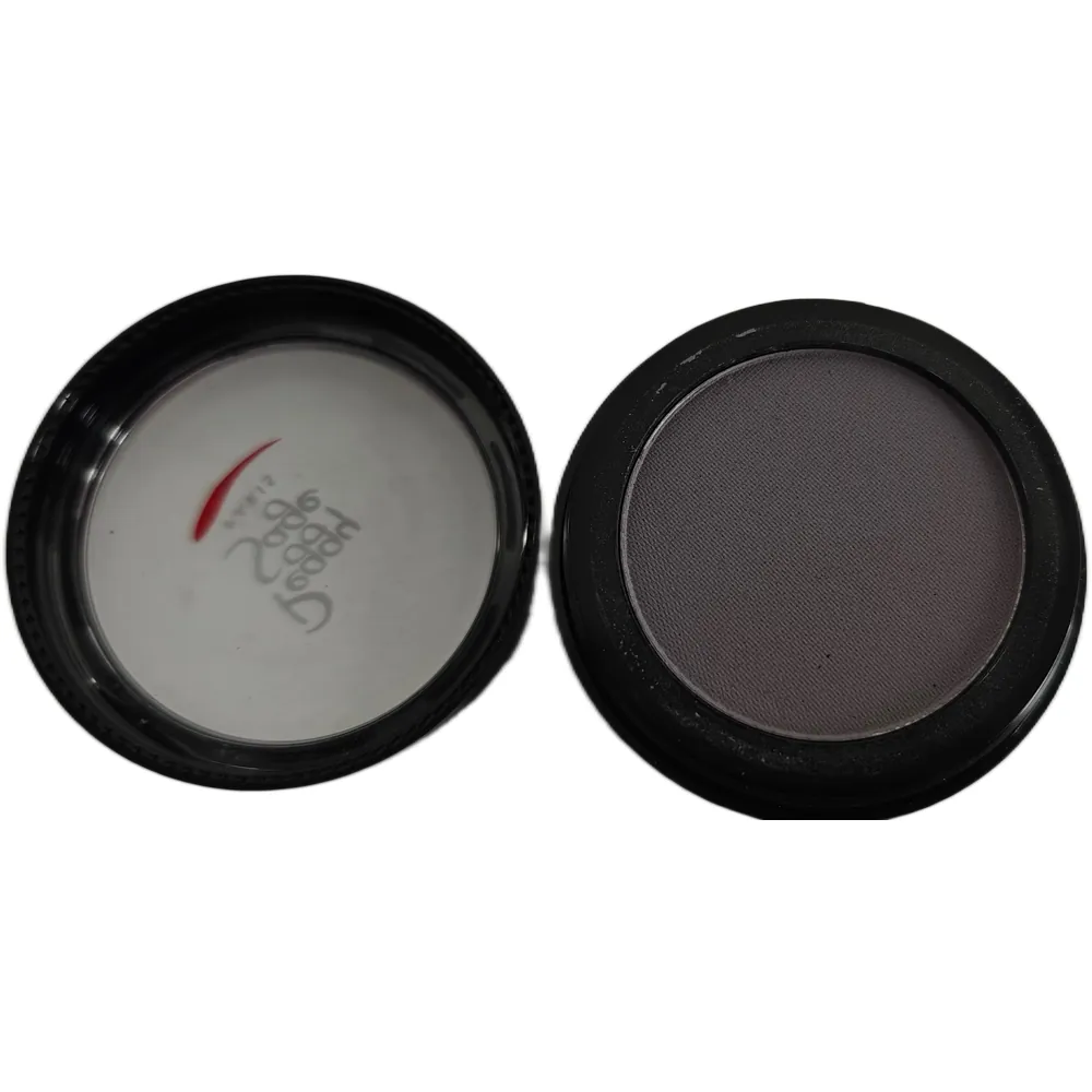 Avattu pyöreä Peggy Sage -luomivärinappi sävyssä Cherished Grey. Oikealla tummanharmaa luomiväri mustassa rasiassa ja vasemmalla puolella läpinäkyvä kansi, jossa näkyy Peggy Sage -logo ja punainen yksityiskohta valkoista taustaa vasten.