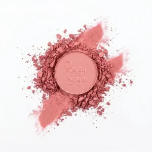 Pyöreä Peggy Sage Lumière Irisée Rose Tendre -luomivärinappi asetteiltuna murennetun roosanvärisen puuteripigmentin ja kimeltävän värisivelyn päälle valkoisella taustalla.