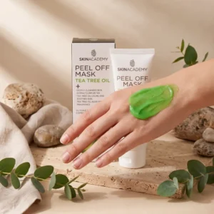 Iholle sivelty raikkaan vihreä Skin Academy Tea Tree Oil Peel Off Mask -kasvonaamio kädenselässä. Taustalla tuotteen pahvipakkaus, valkoinen tuubi, eukalyptuksen oksia ja luonnonkiviä.