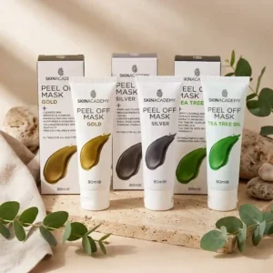 Kolme Skin Academy Peel Off Mask 80 ml -kasvonaamiotuubia ja niiden myyntipakkaukset rivissä kivitasolla: Gold, Silver ja Tea Tree Oil. Ympärillä eukalyptuksen oksia ja luonnonkiviä.