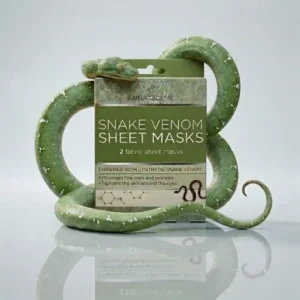 Vihreä Skin Academy Snake Venom -kangasnaamioiden pahvinen myyntipakkaus, jonka ympärille on kietoutunut suurikokoinen, realistinen vihreä käärme. Käärme ja pakkaus lepäävät vaalealla, peilimäisesti heijastavalla alustalla, korostaen tuotteen sisältämää synteettistä käärmeenmyrkkyä.