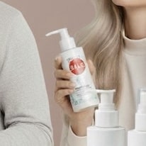 Nainen pitelee valkoista pumppupulloa, jossa on punainen Sale-merkintä.