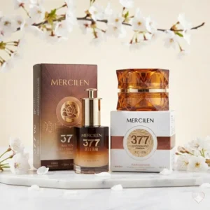 Mercilen 377 -ihonhoitosetti: heleyttävä seerumi ja kasvovoide pakkauksineen marmorialustalla kirsikankukkien keskellä.