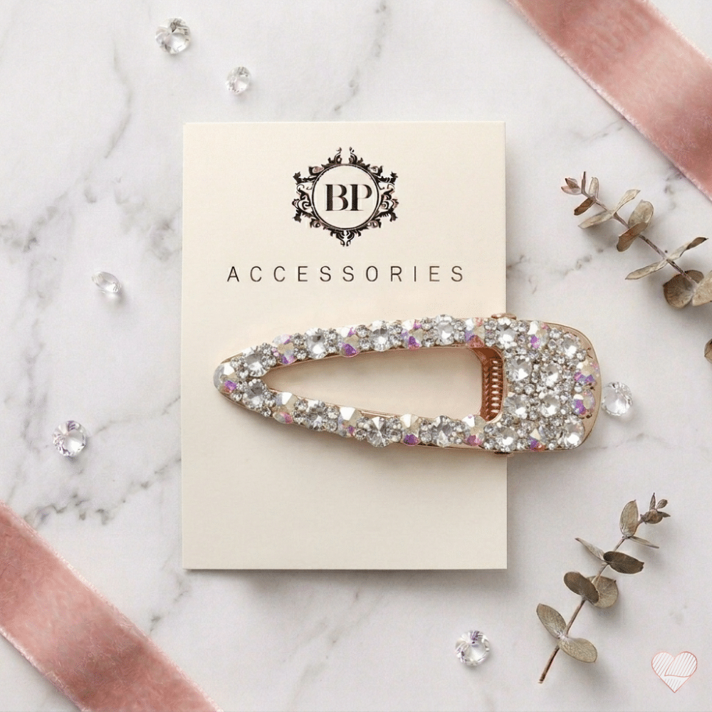 Kullanvärinen pisaranmuotoinen hiussolki, joka on päällystetty kimaltelevilla kirkkailla ja hologrammihohtoisilla strassikivillä.