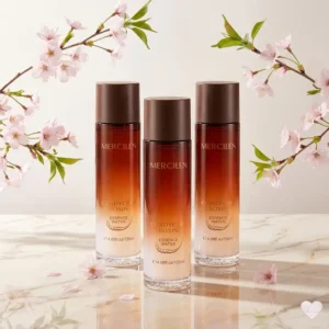Kolme Mercilen Cordyceps Bosin Essence Water -kasvovesipulloa heijastavalla valkoisella marmorialustalla vaaleanpunaisten kirsikankukkien oksien ympäröimänä.
