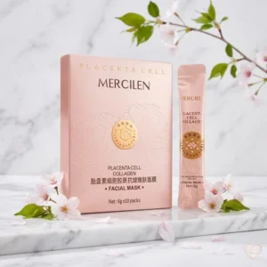 Mercilen Placenta Cell Collagen -kasvonaamion vaaleanpunainen pakkaus ja annospussi marmorialustalla kirsikankukkien ympäröimänä.