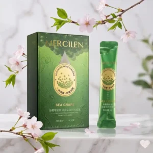 Smaragdinvihreä Mercilen Sea Grape Collagen -tuotepakkaus ja yksittäinen kapea annospussi aseteltuna vaalealle marmorialustalle vaaleanpunaisten kirsikankukkien ja vihreiden lehden ympäröimänä.