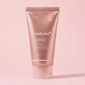 Pystyasennossa korkkinsa varassa seisova metallinhohtoinen, ruusukultaisen vaaleanpunainen Medicube Collagen Night Wrapping Mask -yönaamiotuubi yhtenäisellä vaaleanpunaisella taustalla.