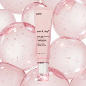 Medicube PDRN Pink Peptide Eye Cream -silmänympärysvoidetuubi ympäröitynä suurilla, läpikuultavilla ja kuplivilla vaaleanpunaisilla vesipalloilla valkoisella taustalla.