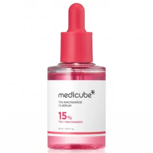 Medicube TXA Niacinamide 15 Serum -kasvoseerumin läpinäkyvä pullo vaaleanpunaisella nesteellä ja vaaleanpunaisella pipettikorkilla suoraan edestä kuvattuna puhtaalla valkoisella taustalla.