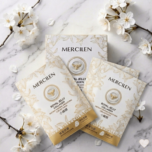 Mercilen Royal Jelly Collagen -kasvonaamiopakkaus ja kaksi yksittäispakattua naamiopussia aseteltuna valkoiselle marmorille, jota ympäröivät vaaleat kirsikankukan oksat.