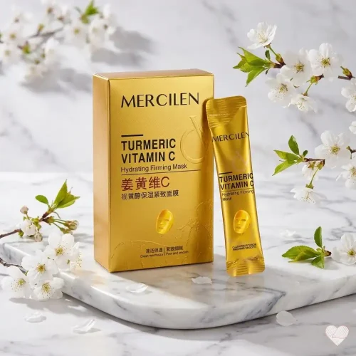 Kultainen Mercilen Turmeric Vitamin C -kasvonaamiopakkaus ja kerta-annospussi vaalealla marmorialustalla, jota ympäröivät valkoiset kirsikankukat ja vihreät lehdet.