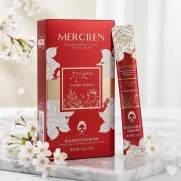 Ylellinen punainen Mercilen Rose Tea Mask -pakkaus ja kapea annospussi aseteltuna marmorialustalle valkoisten kirsikankukkien keskelle.