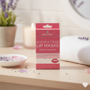 Vaaleanpunainen Skin Academy Hydrating Lip Masks -pakkaus puisella tasolla, taustalla laventelia ja palava kynttilä.